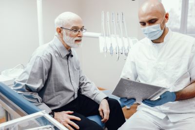Elderly man looks at x-ray with dental team member