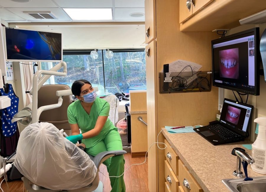 dental hygienist examines child's mouth in mobile dentist unit