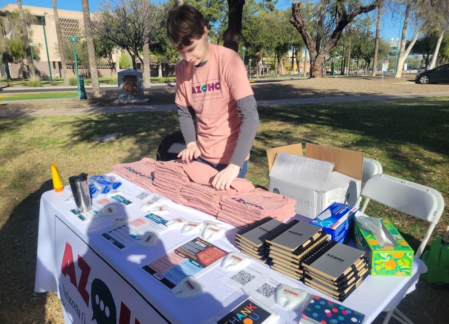 Man stands behind Arizona Oral Health Coalition table