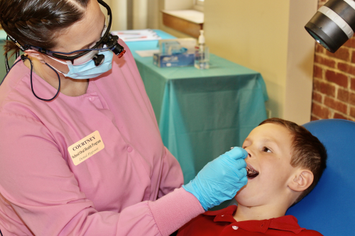 Dental hygienist examines child's teeth