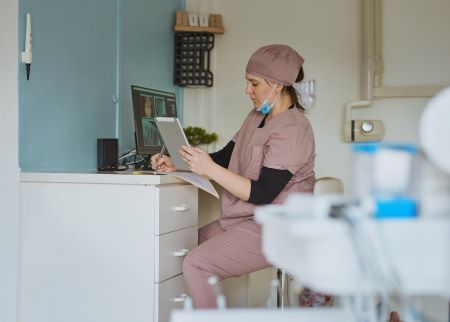 Dental hygienist looking at tablet at desk