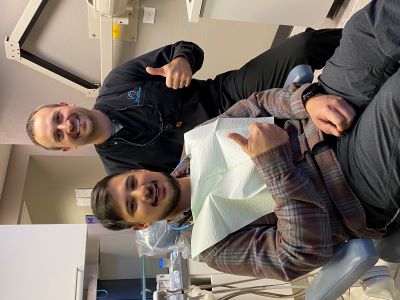 Dental hygienist and patient smiling and giving thumbs up