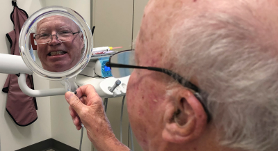 Veteran smiling in the mirror after teeth cleaning