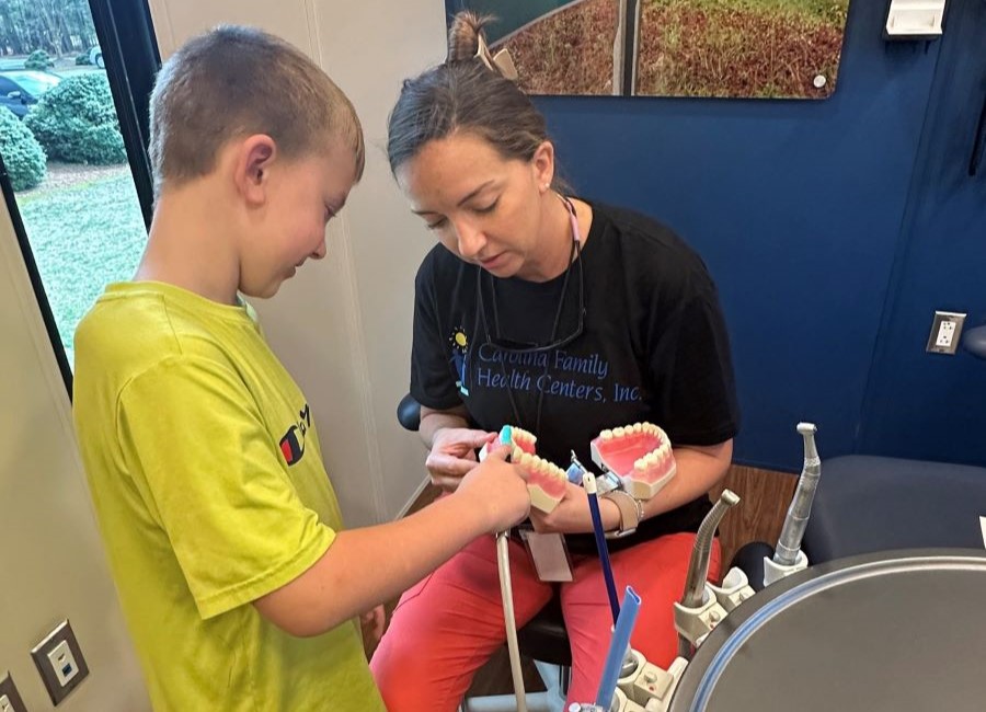 dental hygienist shows child how to brush teeth