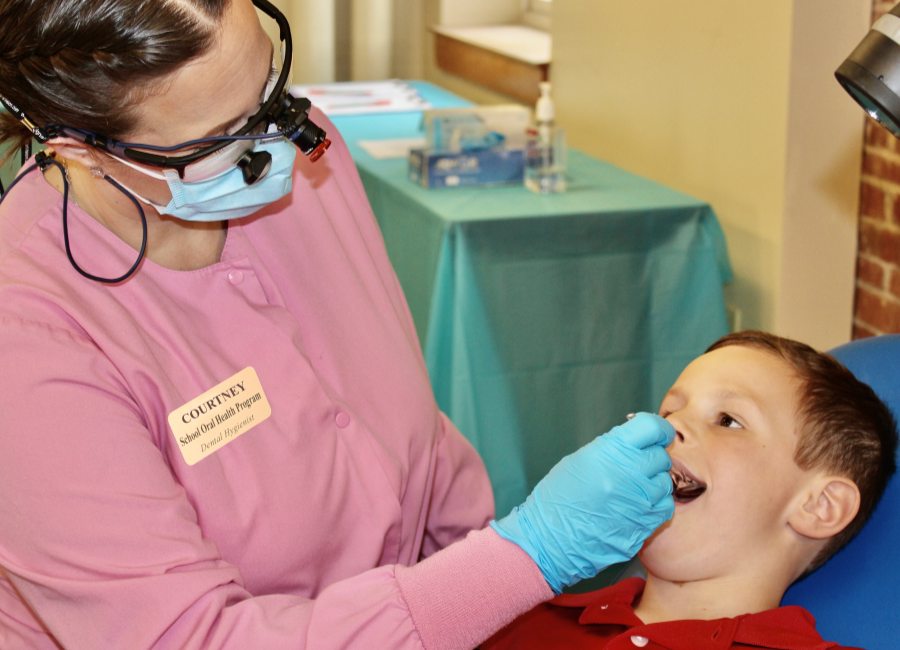 dental hygienist examines child's mouth