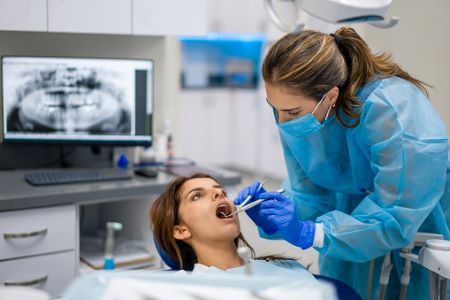 Dental hygienist examines woman's mouth