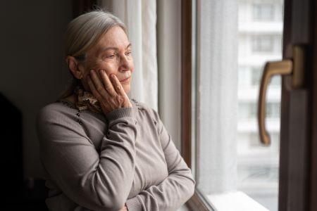 Elderly woman with tooth pain looking out window