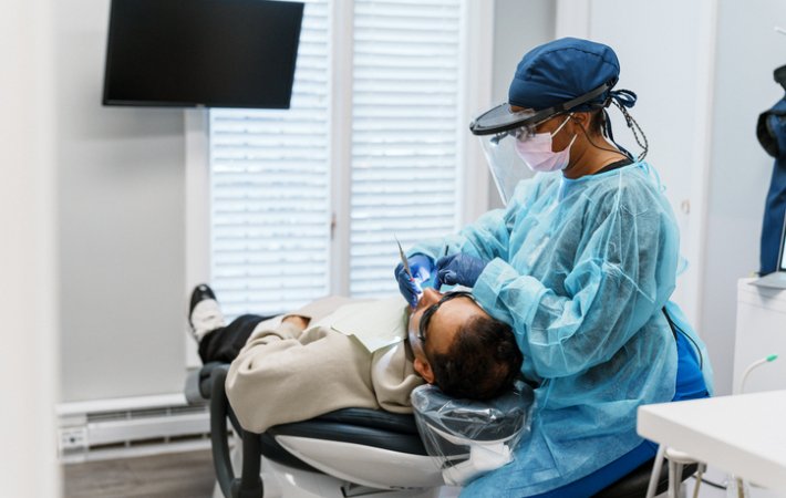 Dental hygienist cleans examines teeth