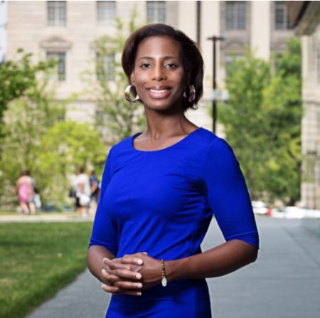 Smiling Woman in a Blue Dress Standing Outdoors on a University Campus.