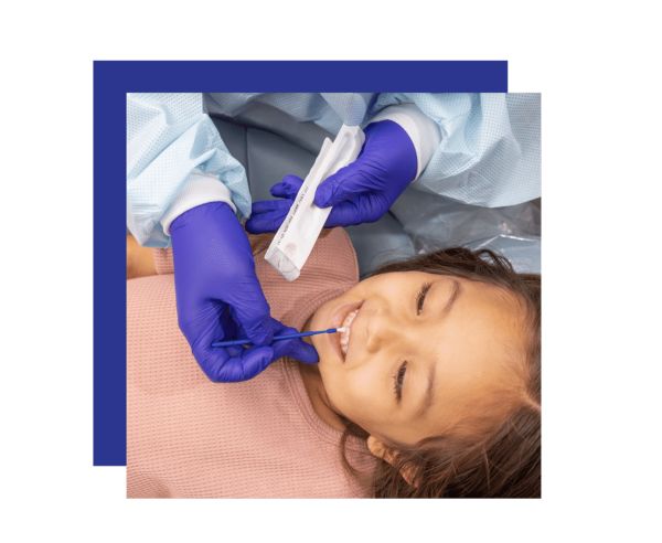 Dental Professional Wearing Purple Gloves and Blue Protective Gown Examines a Smiling Young Girl During a Dental Checkup.