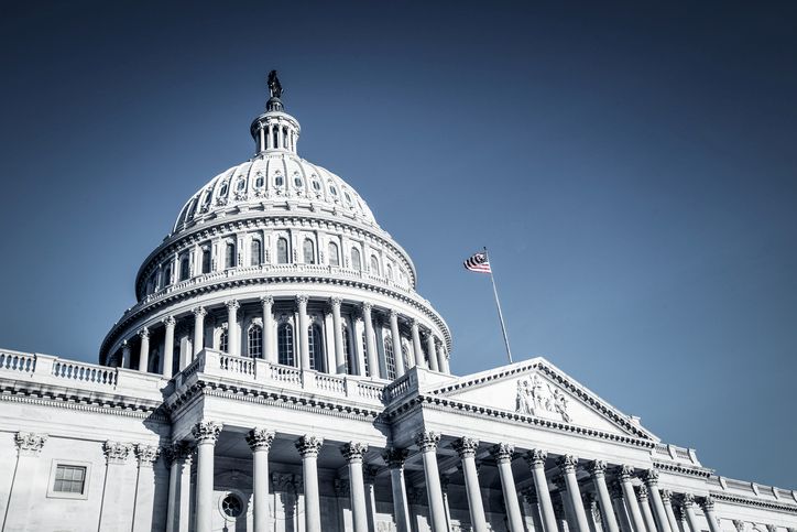 Us Capitol Dome with Flag Flying on a Clear Blue Sky, Viewed from the Front Steps. the Neoclassical Building Features Columns and Arches Across the Facade.
