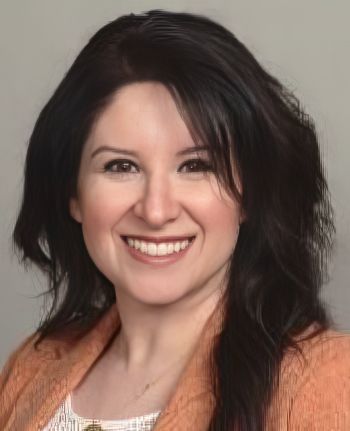Portrait of a Smiling Woman with Dark, Shoulder-length Hair Wearing a Peach Blazer, Neutral Gray Background