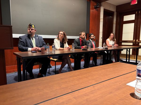Vets Deserve Care Event Panel – CareQuest Institute Panel of Five People Seated at a Long Table in a Conference Room, with Microphones in Front of Them.