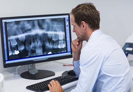 Dentist examining an x-ray on computer in dental clinic