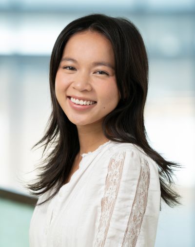 Portrait of a Smiling Woman with Long Dark Hair Wearing a White Lace-detail Blouse, Posing Indoors in Soft Light.