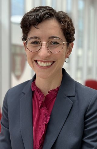 Smiling Woman in a Blazer with Round Glasses, Looking at the Camera.