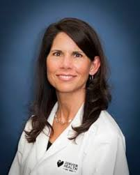 Portrait of a Female Physician in a White Coat Against a Blue Backdrop.