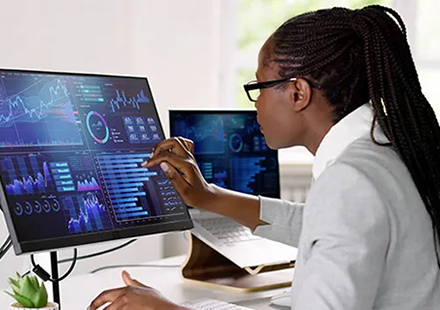 Professional Reviews Colorful Stock Charts on Two Monitor Displays, Analyzing Market Data with a Stylus in Hand.